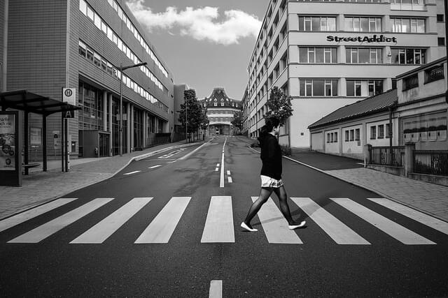 Ein schwarz-weißes Foto einer Person, die einen Zebrastreifen überquert